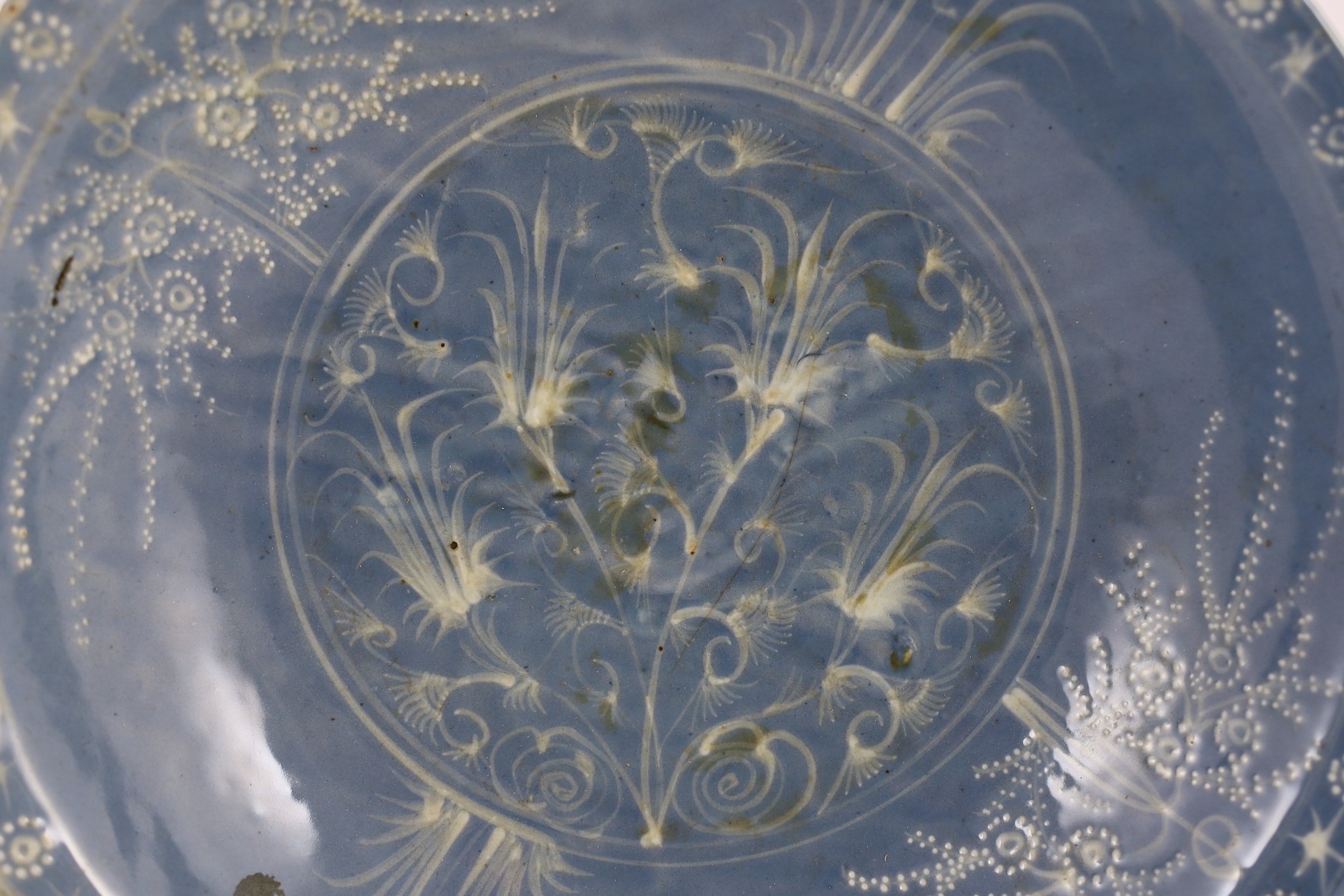 A Chinese Swatow slip-decorated blue glazed deep dish, Zhangzhou kilns, early 17th century, 38cm wide, crack to base